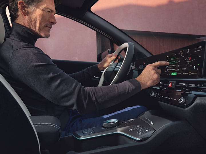 Talent sitzt am Steuer eines Kia Sportage, bedient das Panoramadisplay